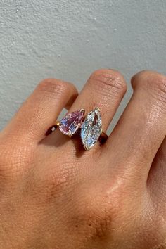 a woman's hand holding an engagement ring with two pear shaped diamonds