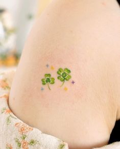 four leaf clover tattoo on the back of a woman's stomach, with little stars around it