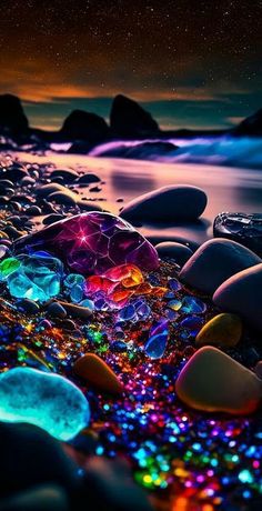 some rocks and water at night with stars in the sky over them, all lit up by colorful lights