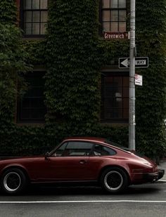 a red sports car parked in front of a tall building with ivy growing on it