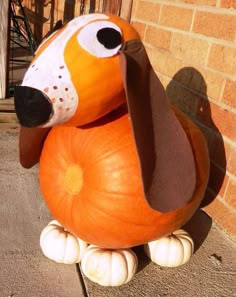 a pumpkin shaped like a dog sitting on top of a cement ground next to a brick wall