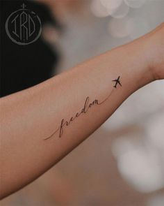 a woman's arm with a tattoo that reads, freedom and an airplane on it