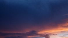 a person flying a kite at sunset on the beach