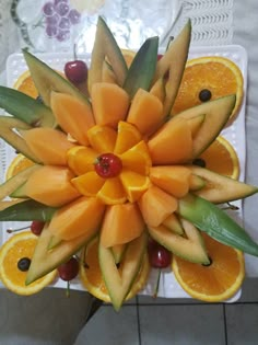 an arrangement of oranges and other fruits arranged in a flower shape on a table