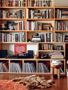 a bookshelf filled with lots of different types of books and cds on top of wooden shelves