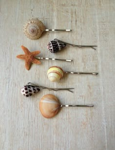 sea shells and seashells are arranged on a wooden table with silver bobby pins