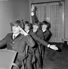 the beatles posing for a photo in an office setting with their hands up to their ears