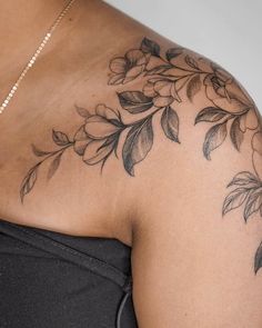 a woman's shoulder with flowers and leaves on it