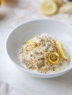 a white bowl filled with food on top of a table next to lemon wedges