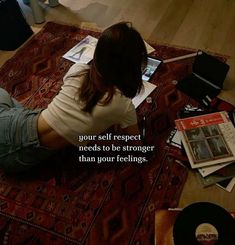 a woman sitting on the floor with her legs crossed and looking at an open book