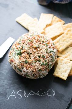 a cheese ball and crackers on a slate board