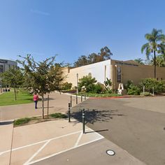 an empty parking lot in front of a building with palm trees on the side walk