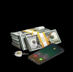 a pile of money sitting next to a cell phone on top of a black surface