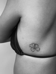 a black and white photo of a woman's stomach with a flower tattoo on it