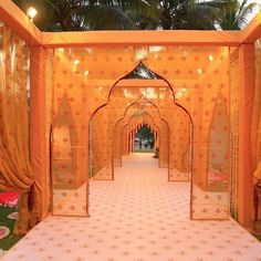 an orange and white wedding setup with draping, flowers and greenery on the floor