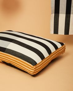 a black and white striped pillow sitting on top of a brown floor next to a lamp