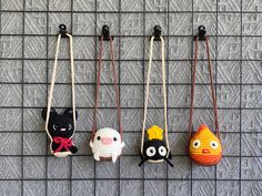 four small crocheted animals hanging from hooks on a gray wall next to each other