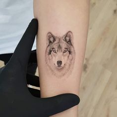 a woman's arm with a wolf tattoo on the left side of her arm