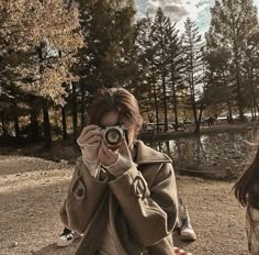 a person taking a photo with a camera in front of some trees and grass,