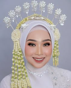 a woman wearing a white headdress with flowers and pearls on her hair is smiling at the camera