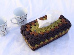 a crocheted tissue holder and coffee cup on a table