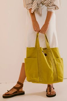 a woman is holding a yellow bag in her hand and wearing sandals on the other side