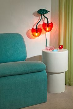 a blue chair sitting next to a white table with two red apples on top of it