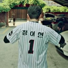 a baseball player is standing in front of a car and holding his arm out to the side