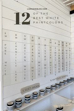 some paint cans are sitting on a shelf in front of a wall with the words 12 off the best white paint colors