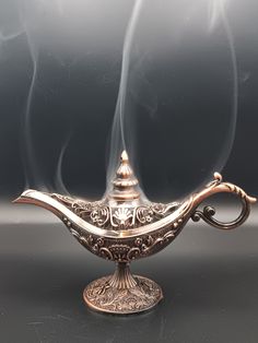 a silver teapot with steam rising out of it's sides on a black surface