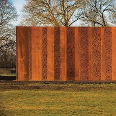 a large metal wall in the middle of a park