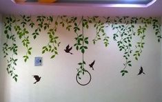 the wall is decorated with green leaves and birds hanging from it's branches,