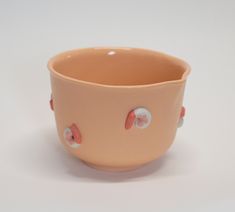 a brown bowl with pink and white polka dots on the rim, sitting on a white surface