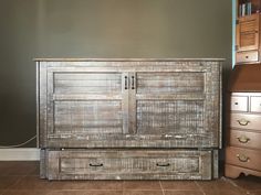 an old wooden cabinet sitting on top of a tile floor next to a dresser with drawers