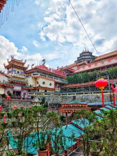 the chinese style buildings are surrounded by greenery and blue sky with clouds in the background