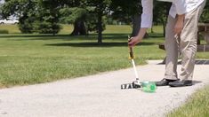 a man is bending over to pick up something off the ground in front of him