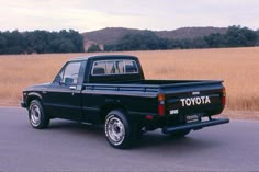 a black toyota pickup truck parked on the side of the road in front of a field