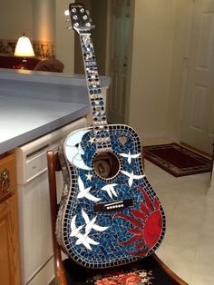 a guitar sitting on top of a wooden chair