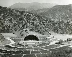 black and white photograph of an outdoor concert venue with mountains in the backgroud