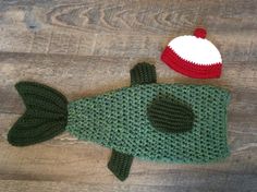 a knitted fish with a red and white hat sitting on top of it's back