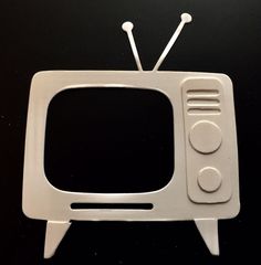 an old fashioned tv sitting on top of a black table next to a remote control