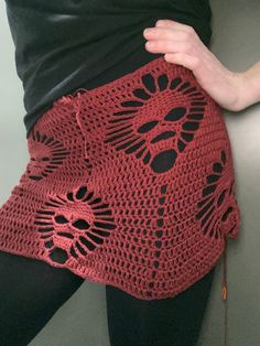 a close up of a person wearing a red crochet skirt with black leggings