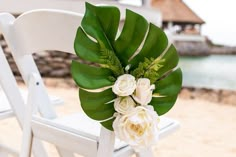 a white chair sitting on top of a sandy beach next to the ocean filled with flowers