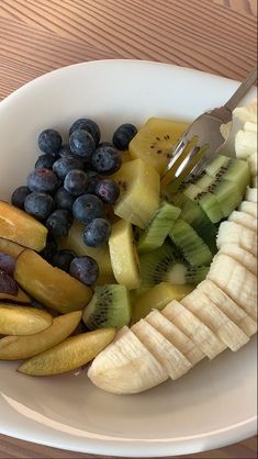 a white plate topped with sliced up fruit and a fork next to some blueberries