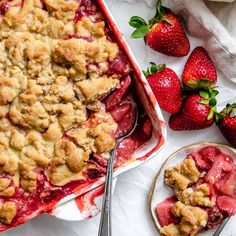 a strawberry cobbler with fresh strawberries on the side and a serving dish next to it