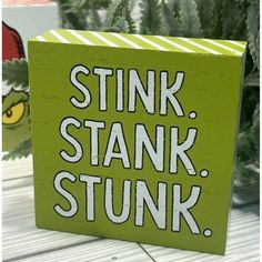 a green sign that says stink, stank, stuk on the side of a plant