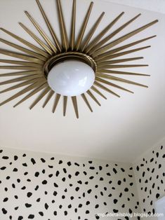 a sunburst light hanging from the ceiling in a room with black and white wallpaper