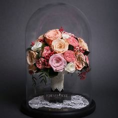 a vase filled with lots of flowers under a glass dome