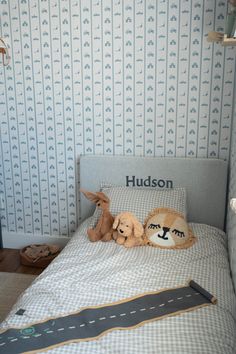 two stuffed animals are on the bed in this child's room with blue and white wallpaper