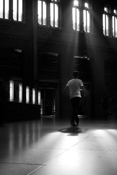 a person with an umbrella is walking through the dark room in front of some windows